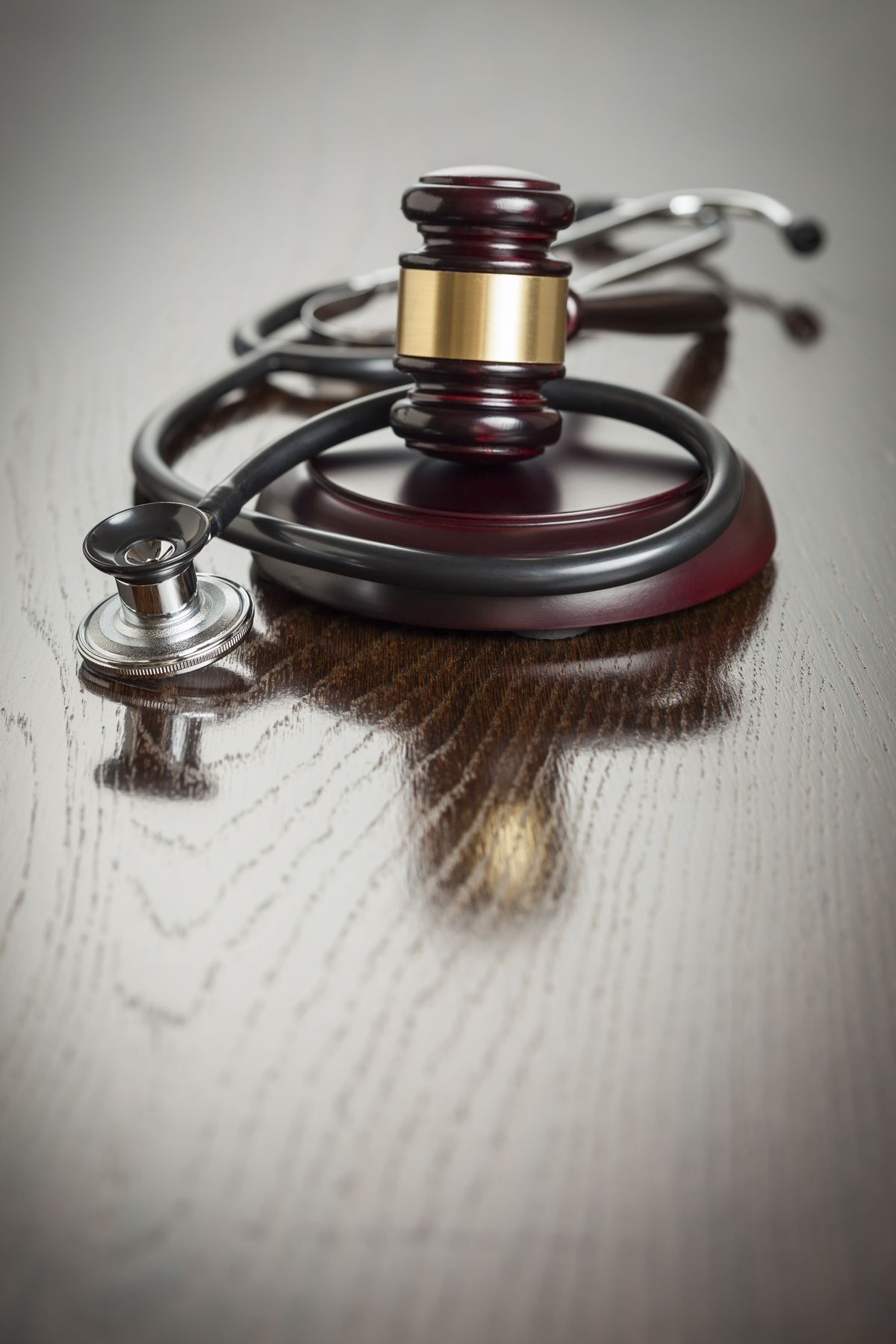 A judge's gavel resting inside a stethoscope on a polished wooden desk