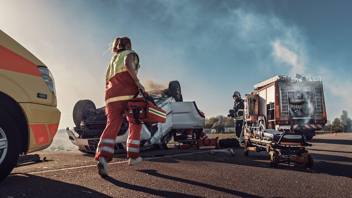 Paramedics and firefighters responding to an overturned car on a road